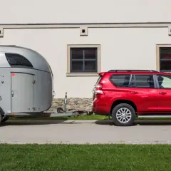 Czerwony SUV holuje przyczepę z koniem. B+E co daje? Możliwość przewiezienia ukochanego zwierzęcia w komfortowych warunkach.