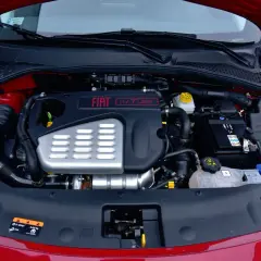 Silnik 1.4 T-Jet w czerwonym samochodzie. Widoczny akumulator, płyny i elementy układu dolotowego.