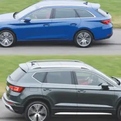 Dwa samochody klasy D: niebieskie kombi i ciemnoszary SUV, jadące obok siebie po drodze.