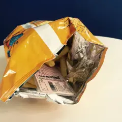 Otwarta paczka chipsów, a w środku etykieta z danymi, jakby to było **prawo jazdy w chipsach**.