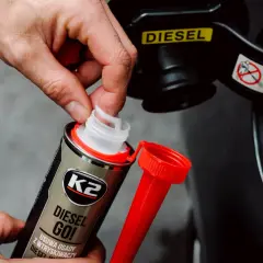 Dłoń otwiera dodatek do paliwa K2 Diesel Go!, który pomaga zapobiegać zamarzaniu diesla. Wskaźnik "DIESEL" na klapce wlewu.