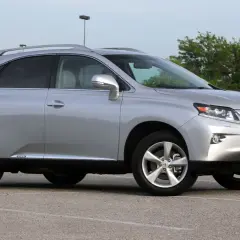 Srebrny Lexus RX 450h, jeden z najmniej awaryjnych SUV-ów 10-letnich, zaparkowany na placu.