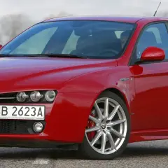 Czerwone Alfa Romeo 159 na drodze. Nawet piękny samochód doświadcza utraty wartości, gdy czas mija.