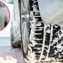 Zimowe opony na śniegu to obowiązek. Policjant kontroluje stan opon, by zapewnić bezpieczeństwo na drodze.
