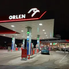 Nocna stacja Orlen z podświetlanym logo. Samochód czeka na tankowanie, bo kiedy tańsze paliwo, warto zatankować.