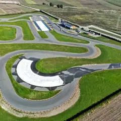 Asfaltowy tor do jazdy samochodem z zielonymi poboczami i zakrętami, idealny do treningów i wyścigów.