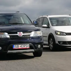 Dwa duże samochody rodzinne, ciemny Fiat i biały Volkswagen, jadą obok siebie po drodze.