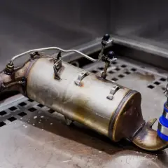 Zużyty filtr cząstek stałych, gotowy do regeneracji. Metalowy element z rurkami i zaciskami.