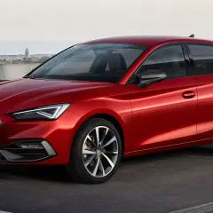Czerwony Seat Leon, auto pochodzenia hiszpańskiego, zaparkowany na tle miasta.