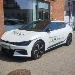 Biały samochód elektryczny Kia z napisem "#GOelectric D do 528 km zasięgu" informuje, ile prądu zużywa samochód elektryczny.