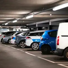 Rząd samochodów na parkingu podziemnym, gotowych do montażu czujników parkowania.