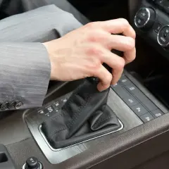 Dłoń kierowcy w garniturze zmienia bieg w samochodzie z automatyczną skrzynią DSG. Proste wskazówki, jak jeździć automatem DSG.