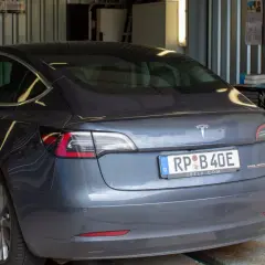 Szary Tesla na podnośniku, mechanik sprawdza, jak dbać o samochód.