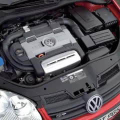 Silnik 1.4 TSI Twincharger w czerwonym Volkswagenie. Widoczny jest blok silnika z logo VW, przewody i elementy układu dolotowego.