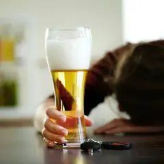 Ręka sięga po piwo, obok kluczyki. Zastanawiasz się, ile promili po jednym piwie? Nie ryzykuj.