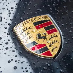 Znak Porsche, symbol luksusowych marek samochodów, lśni po deszczu.