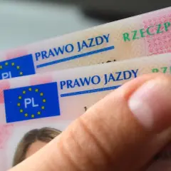 Dłoń trzyma dwa nowe polskie prawo jazdy. Widoczne napisy "PRAWO JAZDY" i godło UE.