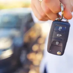 Kluczyk samochodowy z przyciskami, sugerujący jak wyłączyć immobilizer. W tle rozmyty samochód.