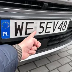 Palec wskazuje hologram na polskiej tablicy rejestracyjnej. Zastanawiasz się, ile czasu na rejestracje auta z zagranicy?