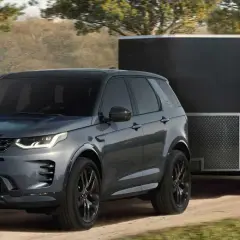 Szare Discovery Sport z przyczepą kempingową na drodze. Idealne auto do przyczepy kempingowej, gotowe na przygodę.