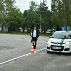 Egzaminator ustawia pachołek, a kursant wykonuje hamowanie awaryjne na placu manewrowym.