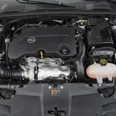 Silnik samochodu Opel z logo marki. Pod maską widać turbosprężarkę i zbiornik płynu chłodniczego. To silnik CDTI, co to znaczy? To silnik Diesla z turbodoładowaniem.