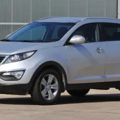 Srebrny Kia Sportage, jeden z najmniej awaryjnych aut terenowych, zaparkowany przed budynkiem.