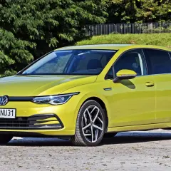 Żółty Volkswagen Golf 8, jeden z wielu popularnych **volkswagen nazwy modeli**, zaparkowany na tle zieleni.
