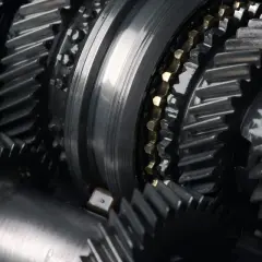Zbliżenie na metalowe koła zębate, sugerujące awarię skrzyni biegów. Widoczne elementy mechanizmu, gotowe do naprawy.
