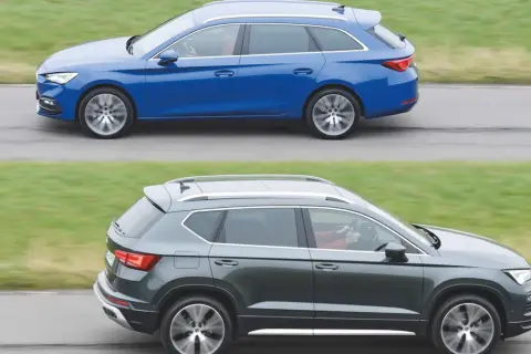 Dwa samochody klasy D: niebieskie kombi i ciemnoszary SUV, jadące obok siebie po drodze.