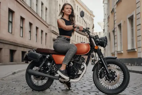 Kobieta na motocyklu, który może być najmocniejsze 125 na b. Stylowy wygląd i miejska sceneria.