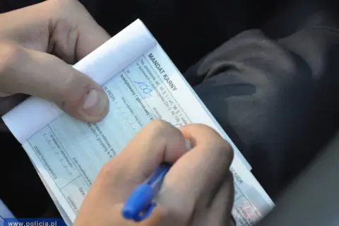 Ręka pisze mandat karny. Zastanawiasz się, ile czasu na zapłacenie mandatu? Sprawdź przepisy.