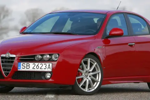 Czerwone Alfa Romeo 159 na drodze. Nawet piękny samochód doświadcza utraty wartości, gdy czas mija.