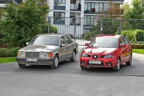 Dwa samochody, srebrny Mercedes i czerwony Seat, stoją obok siebie. To tylko mała część rosnącej ilości samochodów w Polsce.