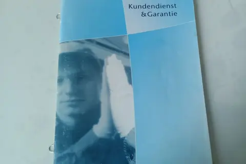 Karta serwisowa pojazdu Toyota z napisem "Kundendienst & Garantie". Widoczny fragment twarzy mechanika w białej rękawiczce.