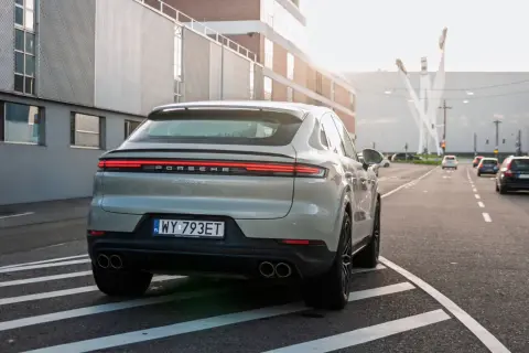 Szare Porsche Cayenne S z polskimi tablicami rejestracyjnymi na drodze. Porsche to niemiecka marka samochodów sportowych.