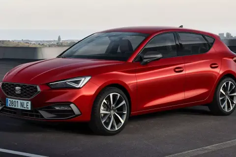 Czerwony Seat Leon, auto pochodzenia hiszpańskiego, zaparkowany na tle miasta.