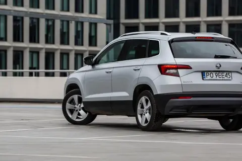 Srebrny Skoda Karoq, jeden z najmniej awaryjnych aut segmentu B, parkuje przed nowoczesnym budynkiem.