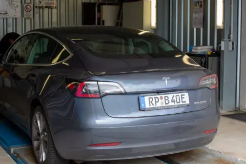 Szary Tesla na podnośniku, mechanik sprawdza, jak dbać o samochód.