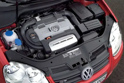 Silnik 1.4 TSI Twincharger w czerwonym Volkswagenie. Widoczny jest blok silnika z logo VW, przewody i elementy układu dolotowego.