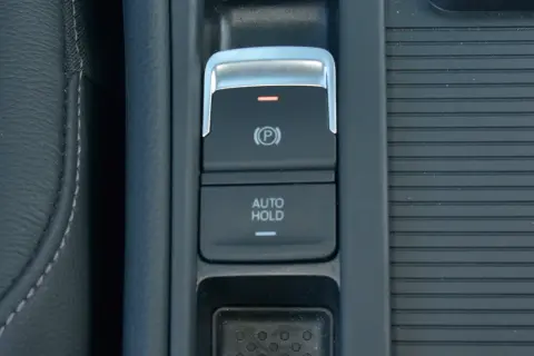 Przycisk AUTO HOLD w samochodzie. To funkcja, która automatycznie utrzymuje pojazd w miejscu po zatrzymaniu.