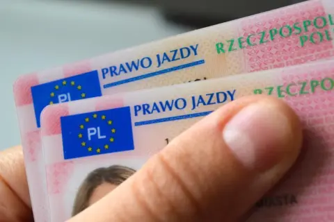 Dłoń trzyma dwa nowe polskie prawo jazdy. Widoczne napisy "PRAWO JAZDY" i godło UE.