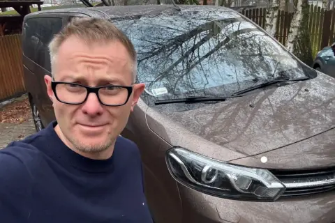 Mężczyzna w okularach przed brązowym autem, zastanawia się, jak szybko sprzedać auto.