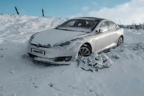 Srebrny Tesla utknął w zaspie śnieżnej. Czy to ogranicza zasięg samochodu elektrycznego w zimowych warunkach?