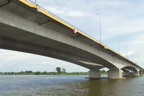 Betonowy most, najdłuższy w Polsce, rozciąga się nad szeroką rzeką, łącząc brzegi w słoneczny dzień.
