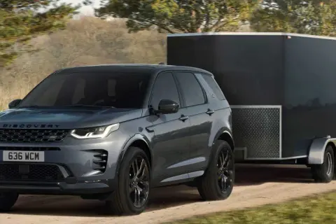 Szare Discovery Sport z przyczepą kempingową na drodze. Idealne auto do przyczepy kempingowej, gotowe na przygodę.