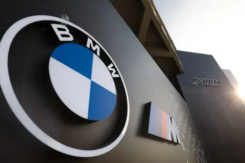 Logo BMW i oznaczenie M, symbole niemieckich marek samochodów, na ciemnej ścianie budynku.