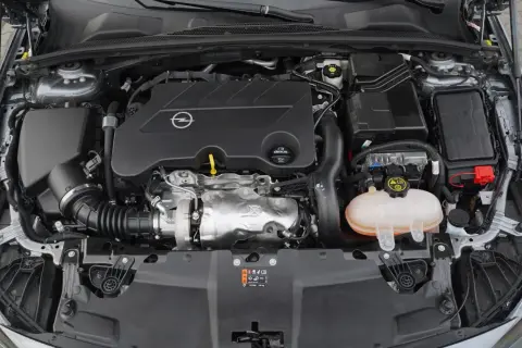 Silnik samochodu Opel z logo marki. Pod maską widać turbosprężarkę i zbiornik płynu chłodniczego. To silnik CDTI, co to znaczy? To silnik Diesla z turbodoładowaniem.