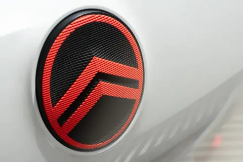 Nowe logo Citroëna w kolorze czarno-czerwonym, z charakterystycznymi jodełkami, zdobi białą karoserię samochodu.