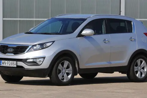 Srebrny Kia Sportage, jeden z najmniej awaryjnych aut terenowych, zaparkowany przed budynkiem.
